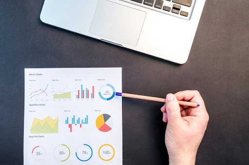 Une personne en train d'analyser une feuille de statistiques devant un ordinateur portable