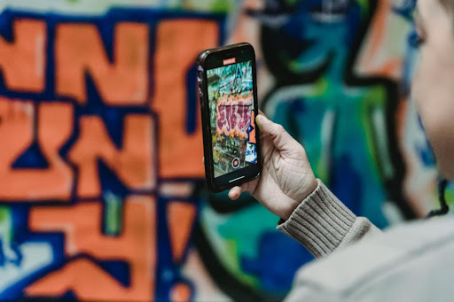 Une personne prends en photo un tag coloré sur un mur avec son smartphone.